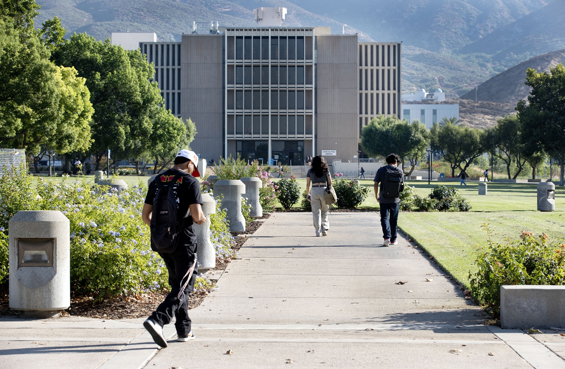 The walkway along the university Pfau Library lawn, with the library, Murillo Family Observatory and the San Bernardino Mountain foothills in the background.