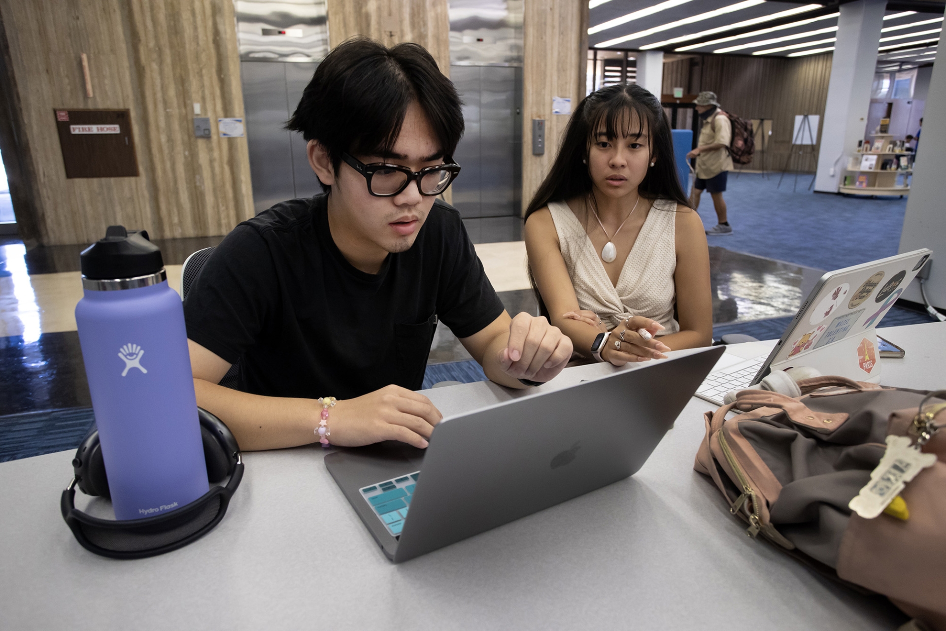 Two students look over a laptop in the Pfau Library.
