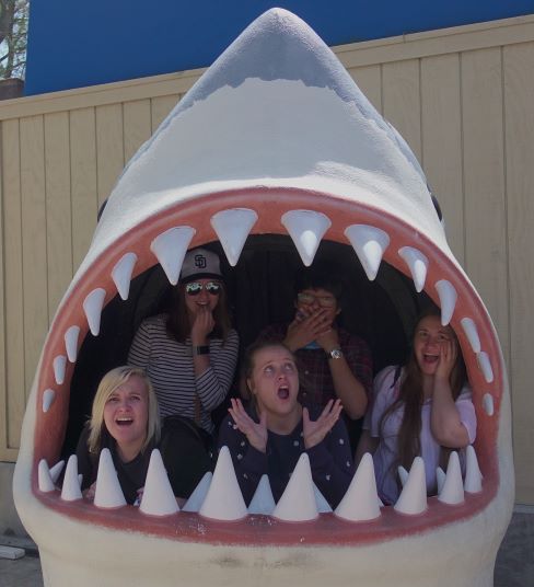 Honors students pose in the mouth of a shark statue.
