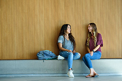 Students leaning against a wall talking