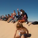 People sliding down sand dunes