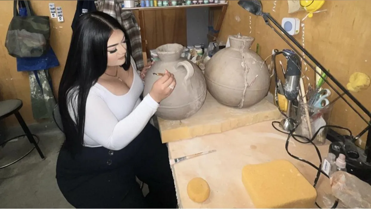 Master of Fine Arts student, Katherine Yvonne Posada, working in their studio, shaping a ceramic vessel that will be part of her thesis exhibition at RAFFMA.