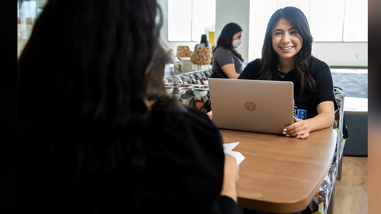 CSUSB student smiling while working on lap top computer