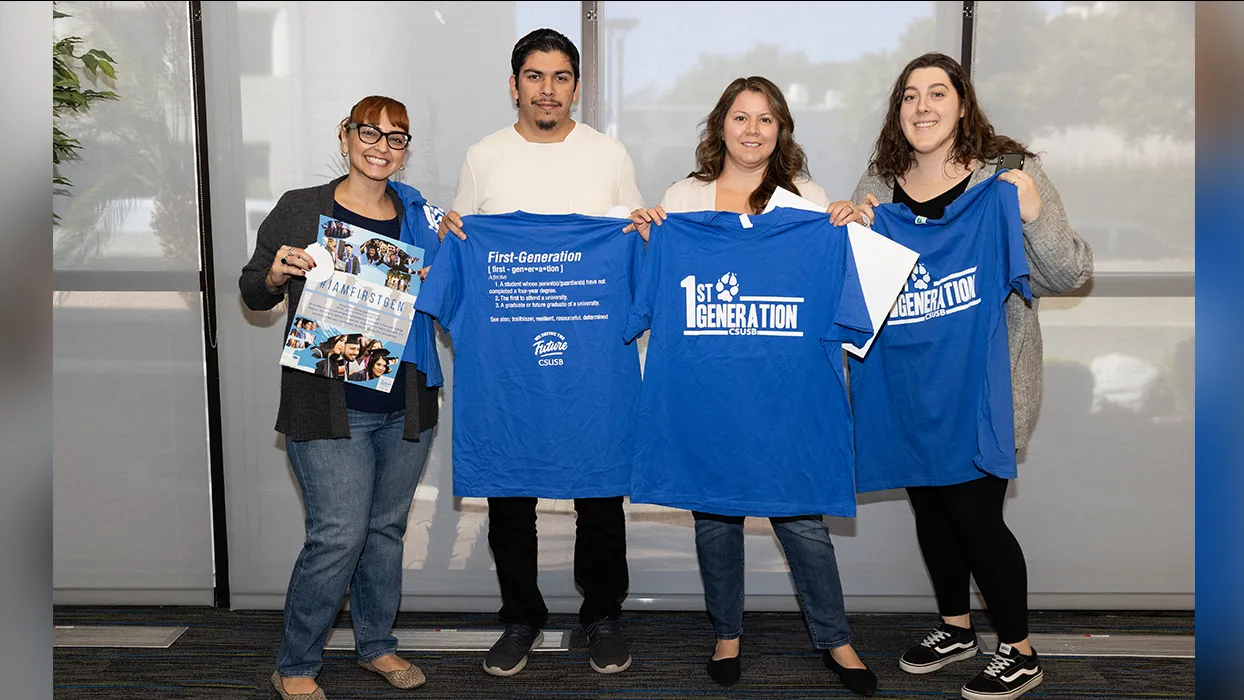 Four attendees hold up first-generation T-shirts they received at the event