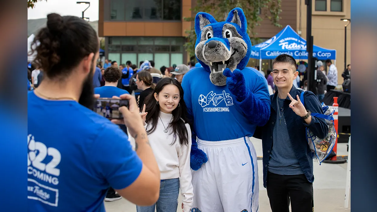 Cody Coyote poses for a picture with a couple of attendees from last year’s Homecoming Bash.