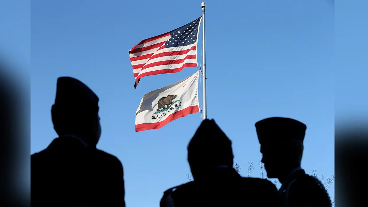 Shadows of military personnel stand near an American flag