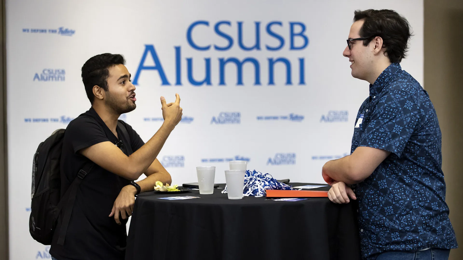 Two people talking at at table. CSUSB Alumni host Amazon Finance Panel session