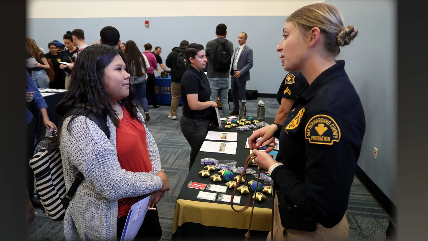 A student and a law enforcement officer meet at the 2020 criminal justice career fair.
