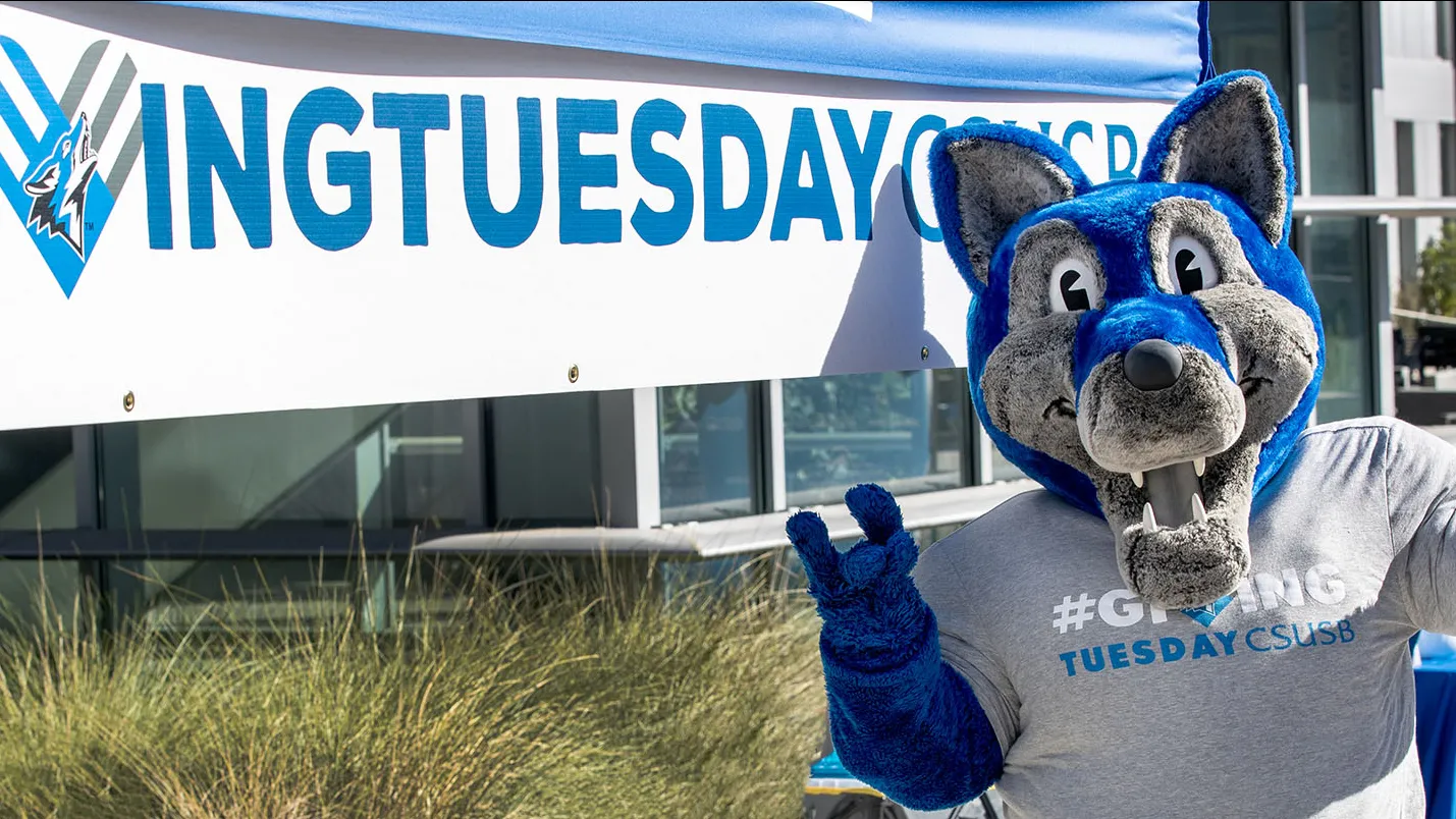 Cody Coyote at a Giving Tuesday sign.