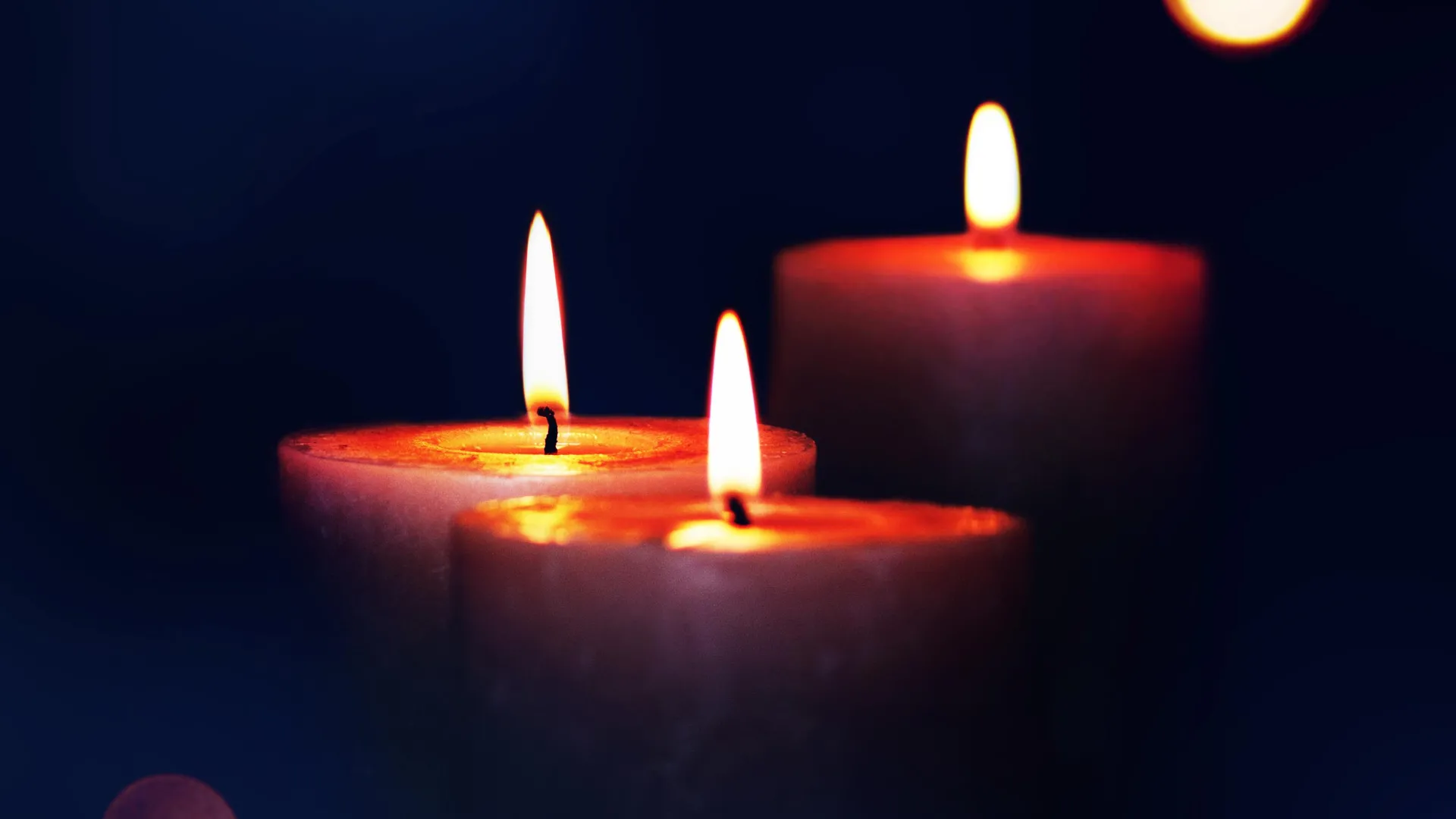 three lit candles in the dark