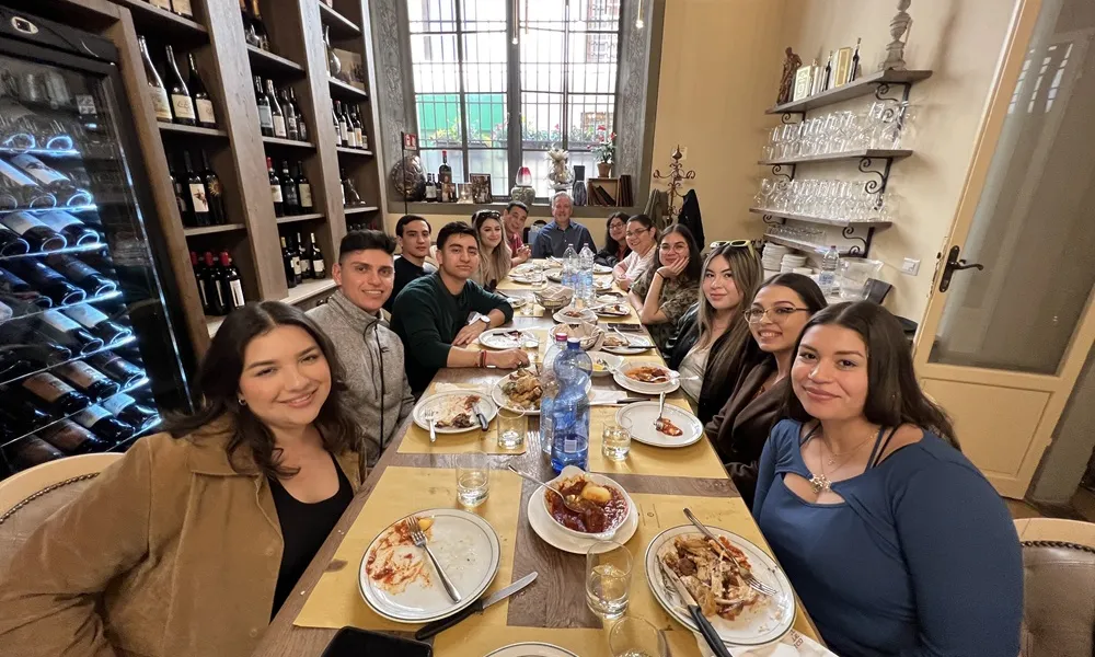 students sitting around a long table dining together in Italy