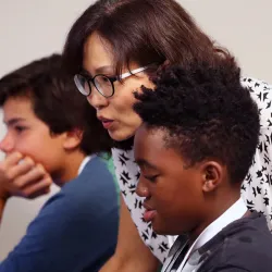 image of teacher helping students with computer