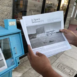 Some holding a copy of the printed zine of "A Space Between Us."  