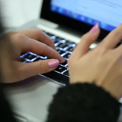 Hands typing on a laptop