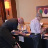  Staff greet guests as they enter the CAE in Cybersecurity Symposium.  Photo by: Staff