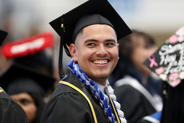 CSUSB graduate smiles in cap and gown.