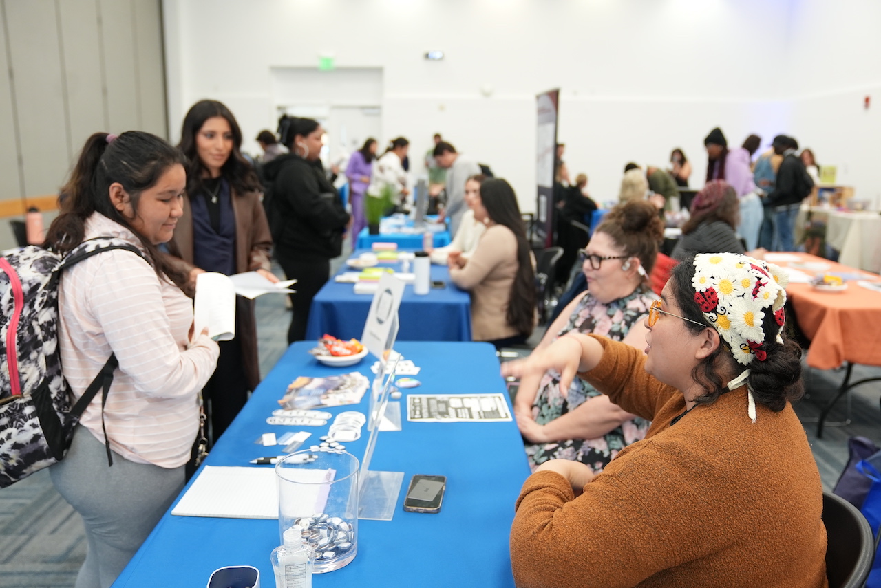 Individuals exploring opportunities at a job fair in a crowded setting.