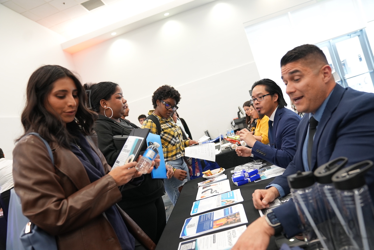 Job fair visitors reviewing information on a table.