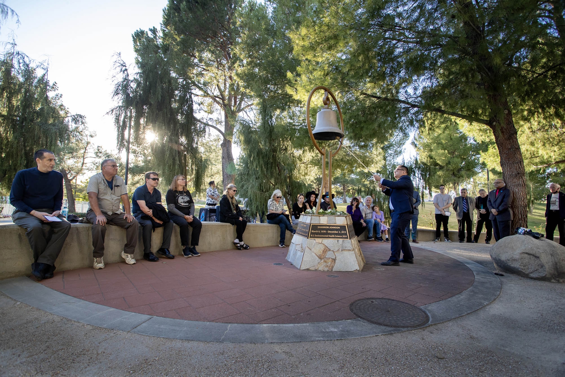 Michael Nguyen, former CNS faculty member, rings the Peace Garden bell 14 times during the Day of Remembrance ceremony on Dec. 2,