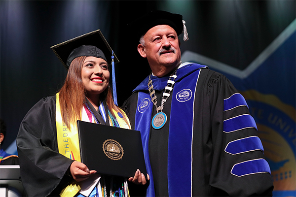 Leticia Herrera at her 2019 graduation with CSUSB President Tomás D. Morales.
