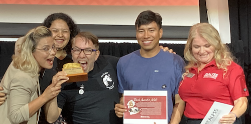 Group of Acto Latino students with Tamal award.  Andres appears to be taking a bite of the award.