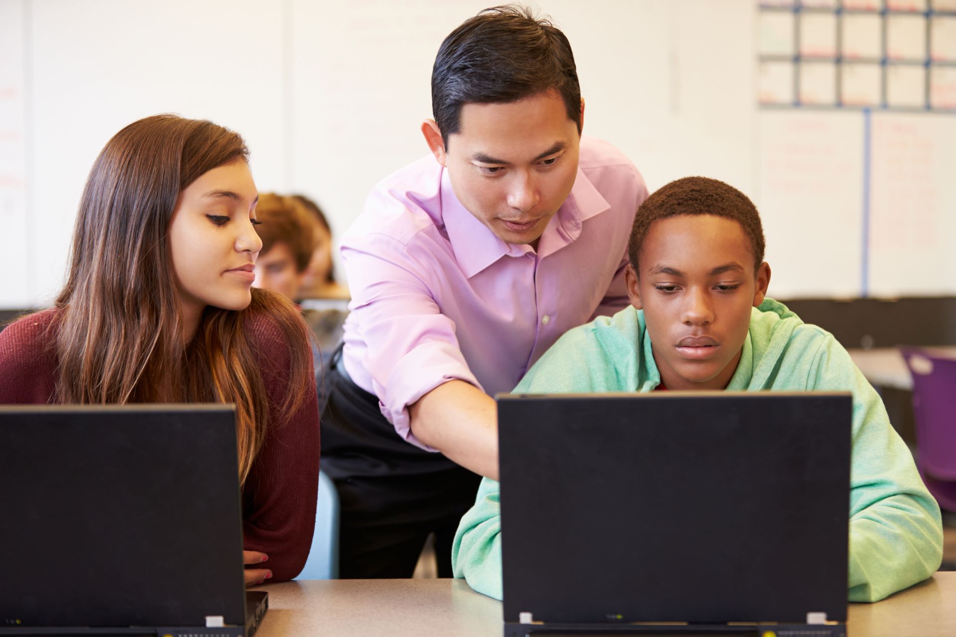 Male teacher showing students on a computer.