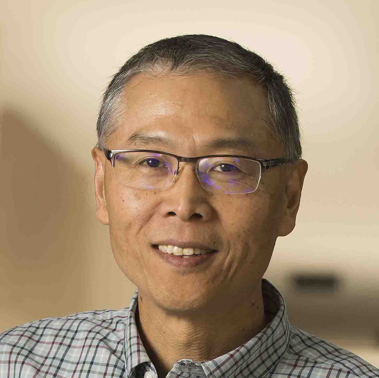 Wang Zuoyue, short grey and black hair, trim Chinese man, glasses and smiling