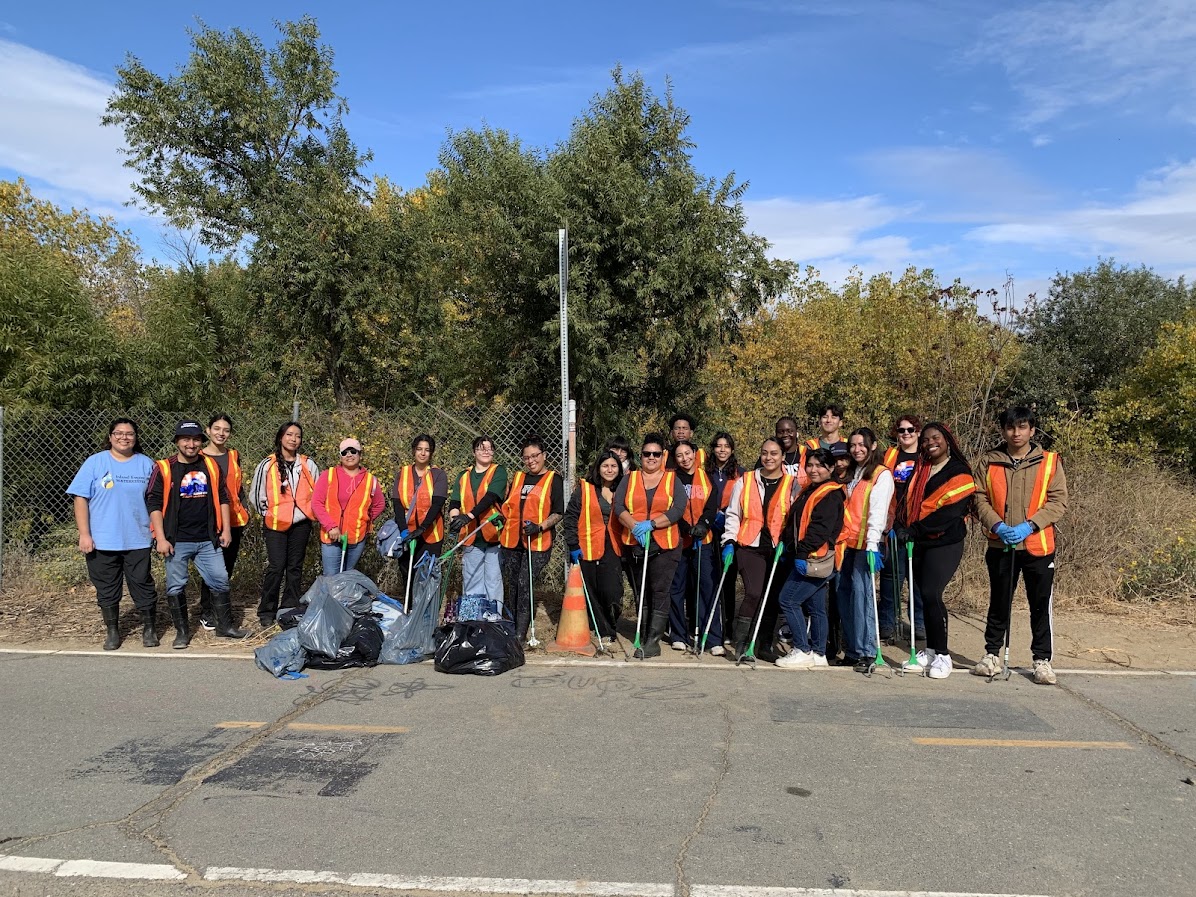 Group photo of students in vests at a park clean up event