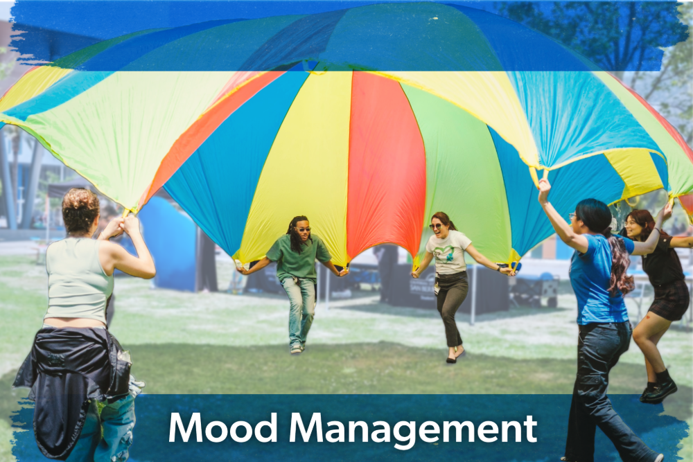 People joyfully lift a large, colorful parachute in a park, promoting teamwork and happiness. The words "Mood Management" are at the bottom.