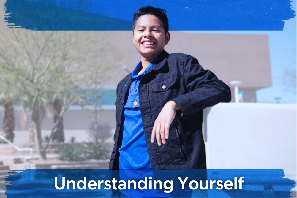 Smiling young person in a blue shirt and black jacket, leaning casually against a light-colored wall outdoors. Text reads "Understanding Yourself."