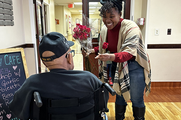 A CSUSB community member handing a flower to a senior.